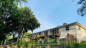 A two-story house with a balcony, surrounded by a garden with various plants and a small pond. - Home w/ hot tub, game room, sauna on Lake Wausau near Granite Peak (Schofield)