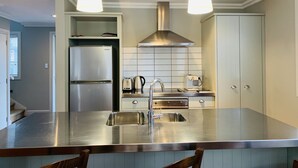 Een moderne keuken met roestvrijstalen apparatuur, een centraal eiland en hanglampen.