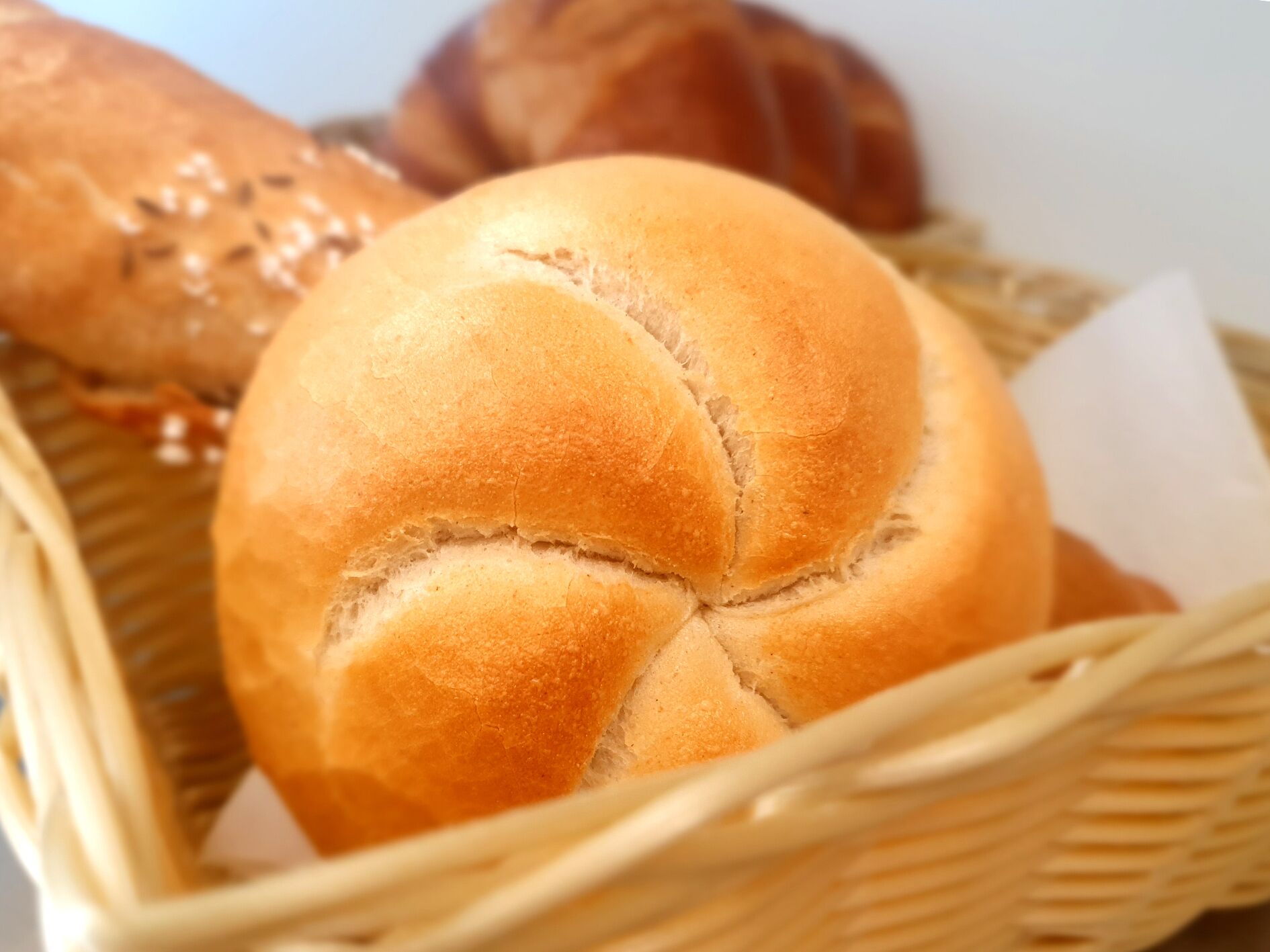Una cesta con hogaza de pan con diseño en forma de cruz.
