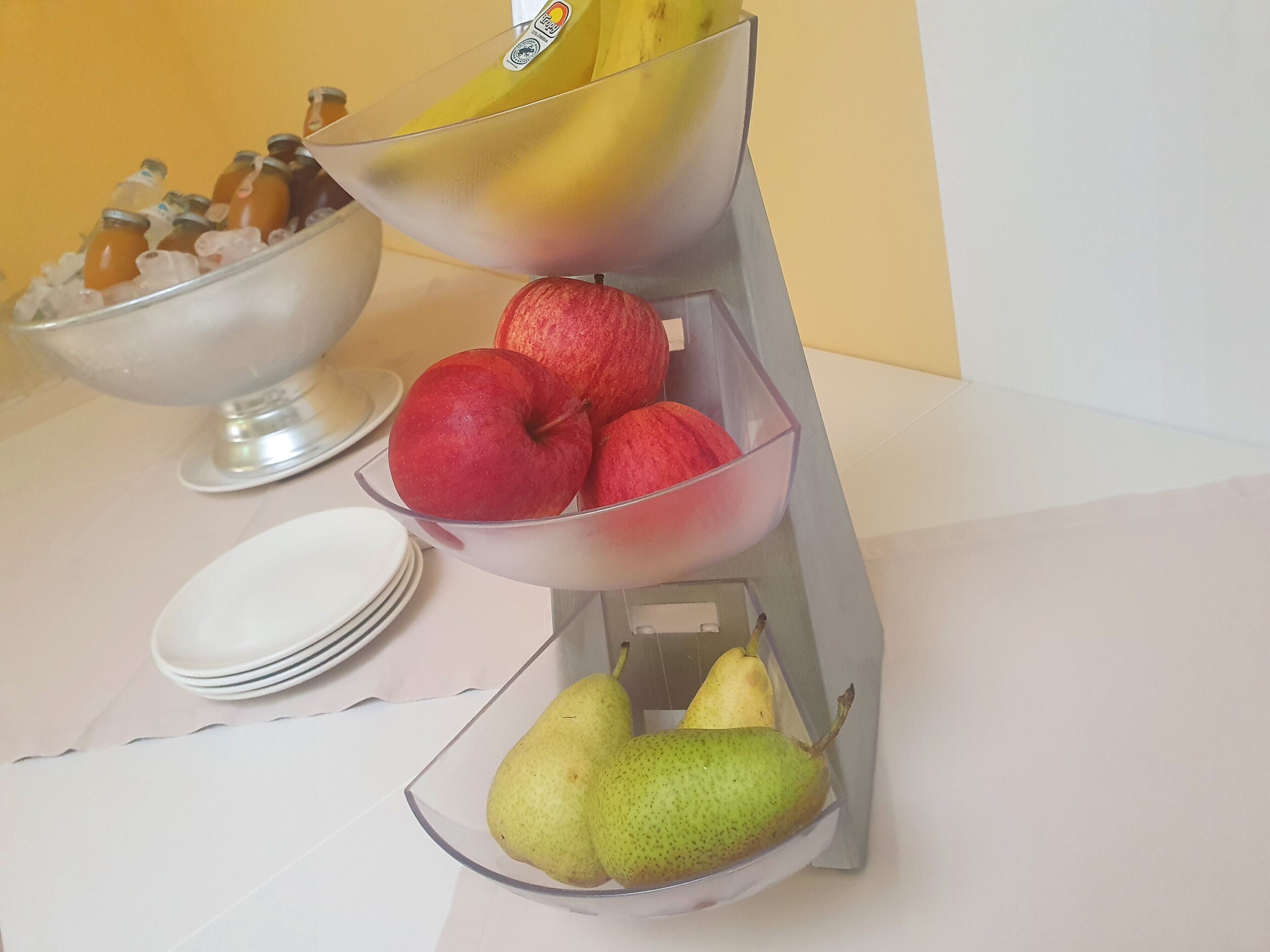 Obstauslage mit Äpfeln, Bananen und Birnen auf einem Tisch.