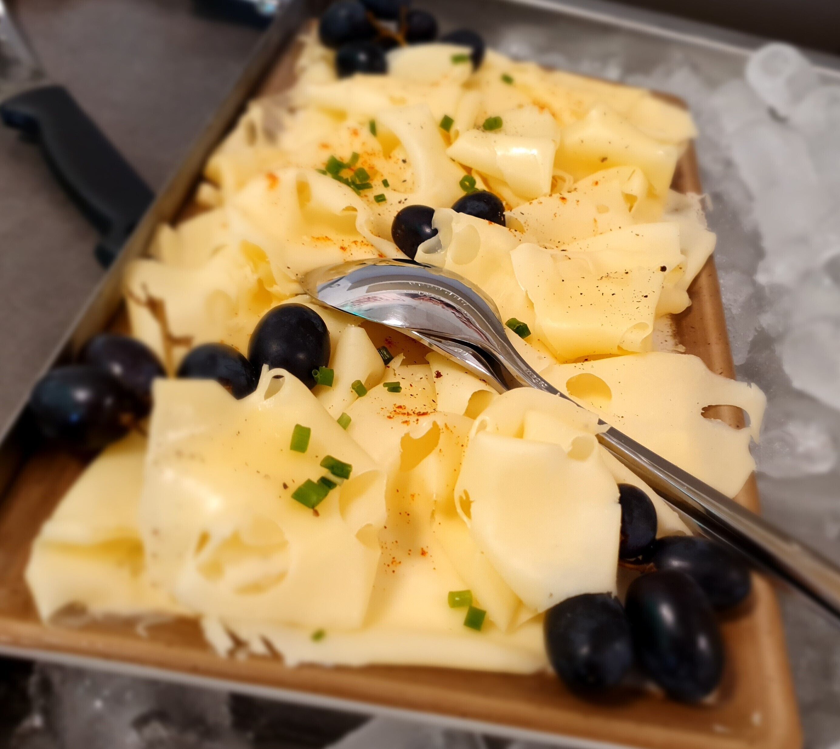 Un piatto di pasta con olive nere e cipollotti su cubetti di ghiaccio.