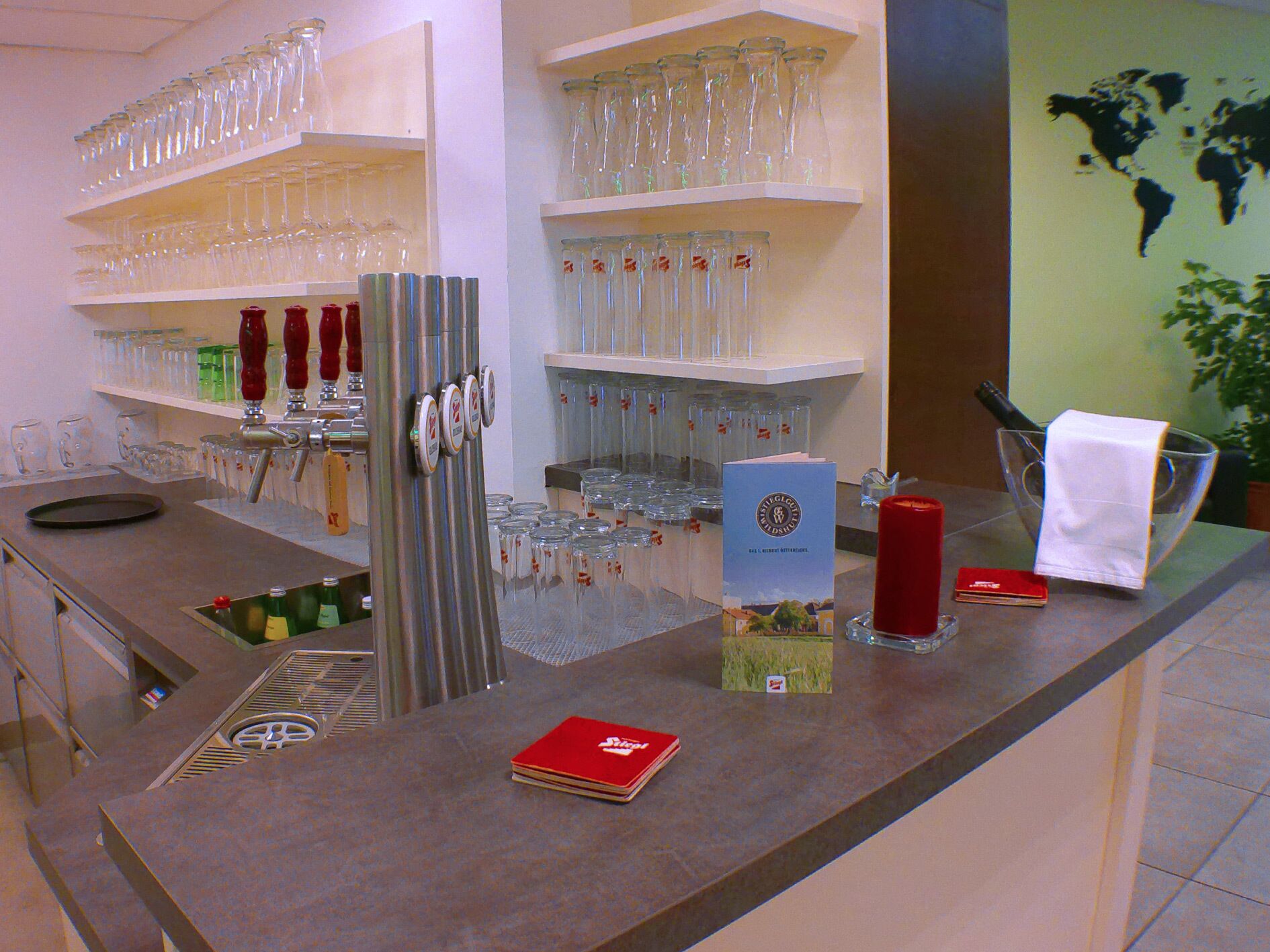 A bar area with shelves of glasses, a beer tap, and a menu stand.