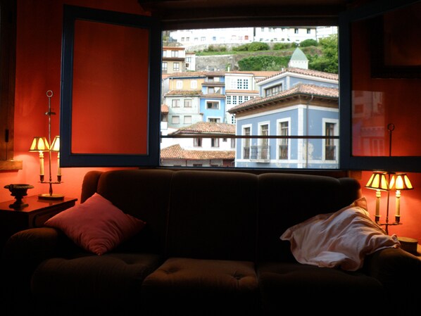 A cozy room with a large window overlooking colorful buildings.
