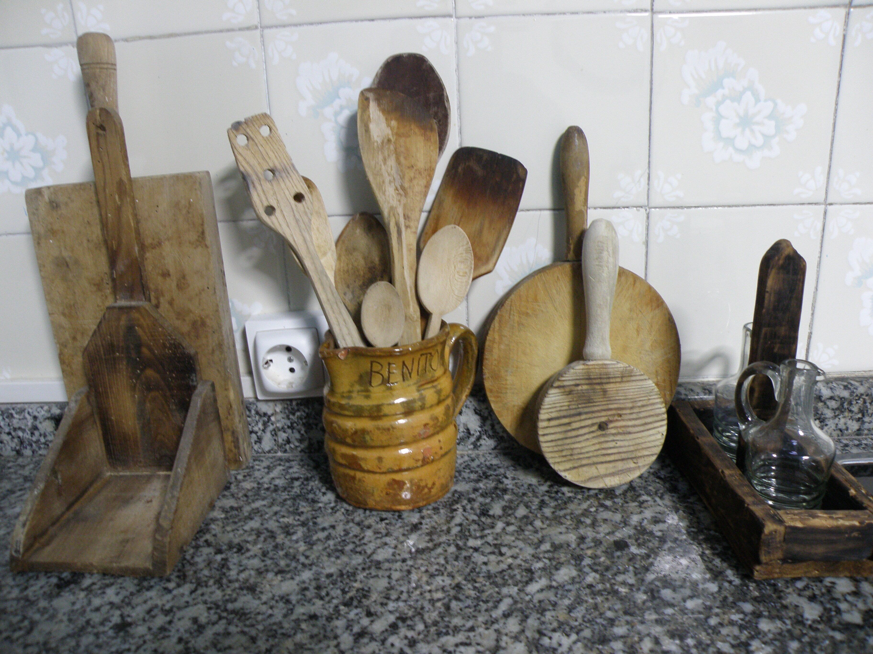Una encimera de cocina con varios utensilios de madera, incluyendo un juego de cucharas de madera, una espátula de madera y un rallador de madera.
