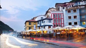A cobblestone street lined with colorful buildings, outdoor seating areas, and a view of the water. - SANTA JULINA (best viewpoint of all Cudillero) (Cudillero)