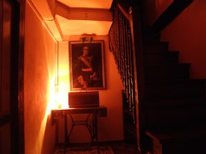 Staircase with a framed portrait above a table and a lamp, leading to a hallway.