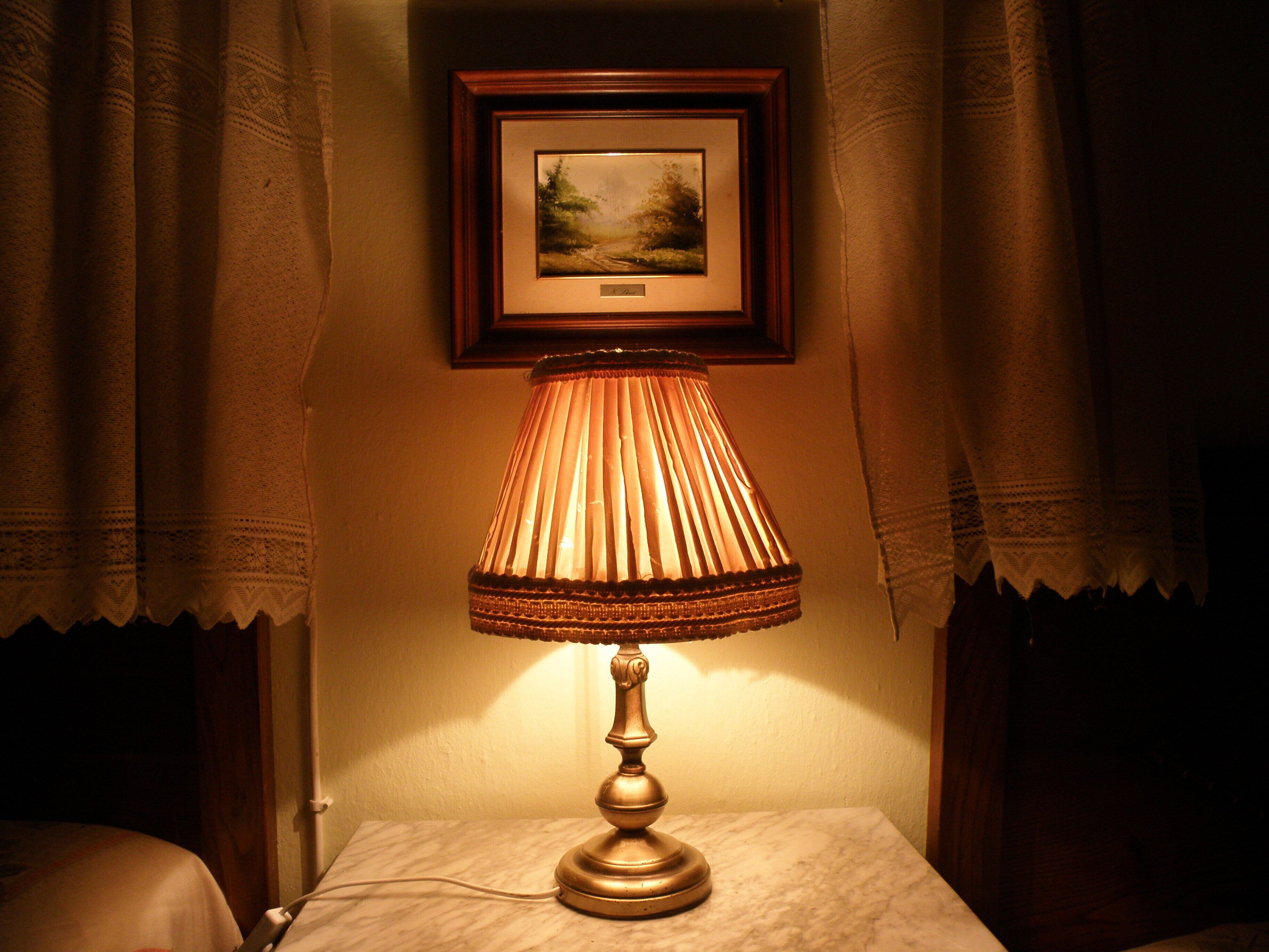 Une lampe sur une table, avec un tableau encadré au-dessus.