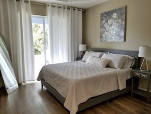 A bedroom with a large bed, two bedside tables with lamps, a window with curtains, and a floral painting on the wall. - Beautiful Vacation House Close to the Beach (Venice)