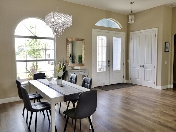 A spacious dining area with a long table, multiple chairs, and a chandelier. - Beautiful Vacation House Close to the Beach (Venice)