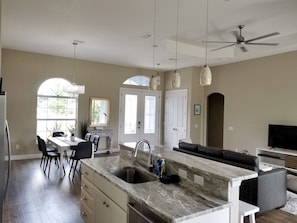 A spacious kitchen with a large island, a dining area with a table and chairs, and a living area with a sofa and TV. - Beautiful Vacation House Close to the Beach (Venice)