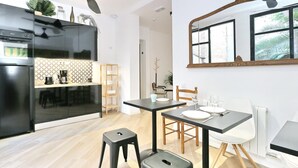 Een moderne keuken met een zwarte koelkast, een houten eettafel met stoelen en een plafondventilator.