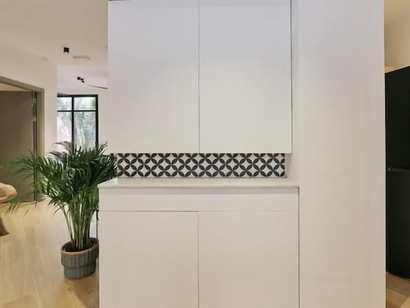 Una cocina moderna con armarios blancos, un salpicadero decorativo y una planta en maceta.