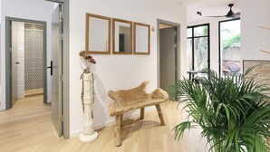 Un intérieur moderne avec un banc en bois, une plante en pot et trois miroirs encadrés accrochés au mur.