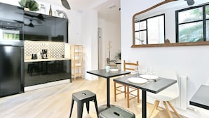 Une cuisine moderne avec un réfrigérateur noir, une table à manger en bois avec des chaises et un ventilateur de plafond.