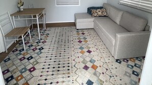 Un espace de vie compact comprenant un canapé, une petite table et un tapis à motifs.
