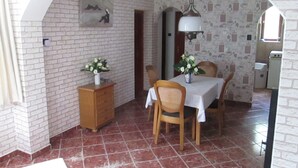 Uma sala de jantar com parede de tijolos, um armário de madeira e piso ladrilhado.