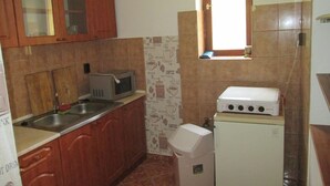 Uma cozinha compacta com armários de madeira, micro-ondas, pequena geladeira e janela com vista para o exterior.