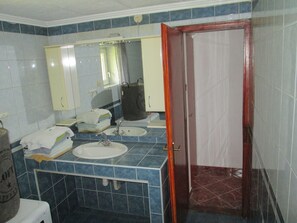 Ein Badezimmer mit zwei Waschbecken, einem Spiegel und einer Tür zu einem Duschbereich.