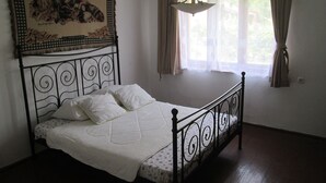 Quarto com cama, janela com cortinas e tapeçaria pendurada.