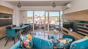 Un salon moderne avec un canapé, un téléviseur et un coin repas.