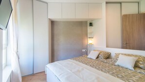 Une chambre à coucher avec un lit, une armoire, un miroir et une fenêtre.