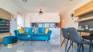 Un salon moderne avec un canapé de couleur turquoise, une table basse et un coin repas avec des chaises.