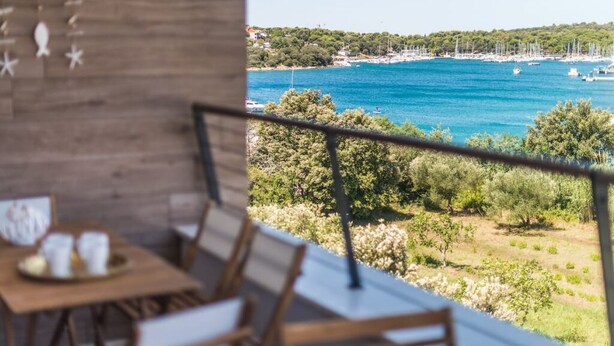 Un balcon offrant une vue sur une zone côtière, avec des bateaux et de la végétation.