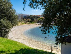 Ein freier Blick auf einen Strand mit einem eingezäunten Bereich, einem Gebäude im Hintergrund und Bäumen, die die Szene einfassen.