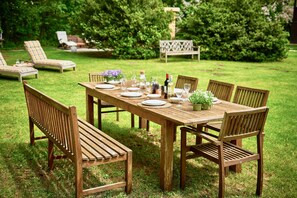 Un conjunto de mesa y sillas de madera para comedor exterior, rodeado de abundante follaje.