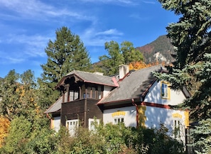A two-story house with a steep roof, surrounded by trees and a mountain in the background. - Landhaus Dodo - Garten Apartment mit Einem SZ - Top 3 - Landhaus Dodo (Payerbach)