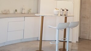 A modern kitchen with white cabinets, a glass-top island, and a wooden ceiling. - Studio Indépendant Villa (Mougins)