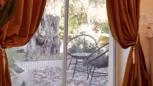 A room with a large sliding glass door, brown curtains, a potted plant, and an air conditioning unit. - Studio Indépendant Villa (Mougins)