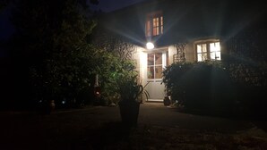 Ett hus i mörkret med en upplyst entré och ett synligt fönster.