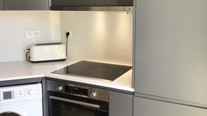 A compact kitchen with a built-in washing machine, a toaster, and a stove. - Elegant 3 rooms. Tennis pool and greenery. (Antibes)