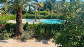A pool surrounded by palm trees and lush greenery. - Elegant 3 rooms. Tennis pool and greenery. (Antibes)