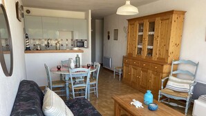 Una sala de estar acogedora con un sofá, una mesa de centro de madera y un comedor con sillas y una mesa.