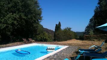 Une piscine avec des chaises longues et une terrasse en pierre.