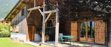 A wooden cabin with a porch, a dining area, and a view of the mountains.