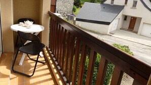 A balcony with a table and chairs, overlooking a residential area with houses and greenery.