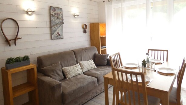 A cozy living area with a sofa, wooden side tables, and a dining table set for two.