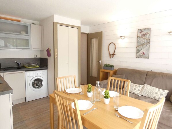 Un espacio habitable compacto con kitchenette, comedor y sofá.