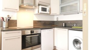 A compact kitchen with a dishwasher, oven, microwave, and washing machine.