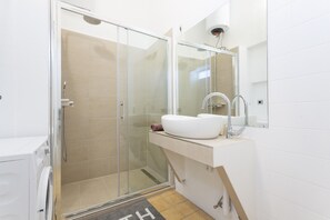 A modern bathroom with a glass-enclosed shower, a white sink, and a mirror above it.