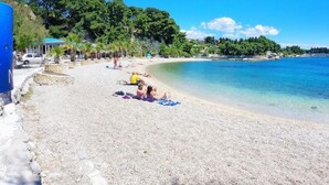 A beach with clear water, people sunbathing, and a rocky shoreline. - Comfortable Apartment With Balcony & Garden View (Split)