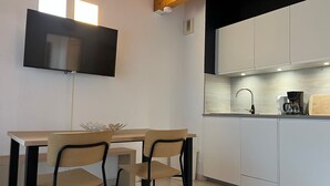 Una cocina moderna con armarios blancos, una mesa de comedor de madera y dos sillas.