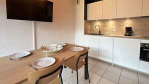 Una cocina moderna con armarios blancos, una encimera de madera y un televisor empotrado.