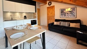 Una cocina moderna con armarios blancos, techo de madera y una mesa de comedor lista para cuatro.