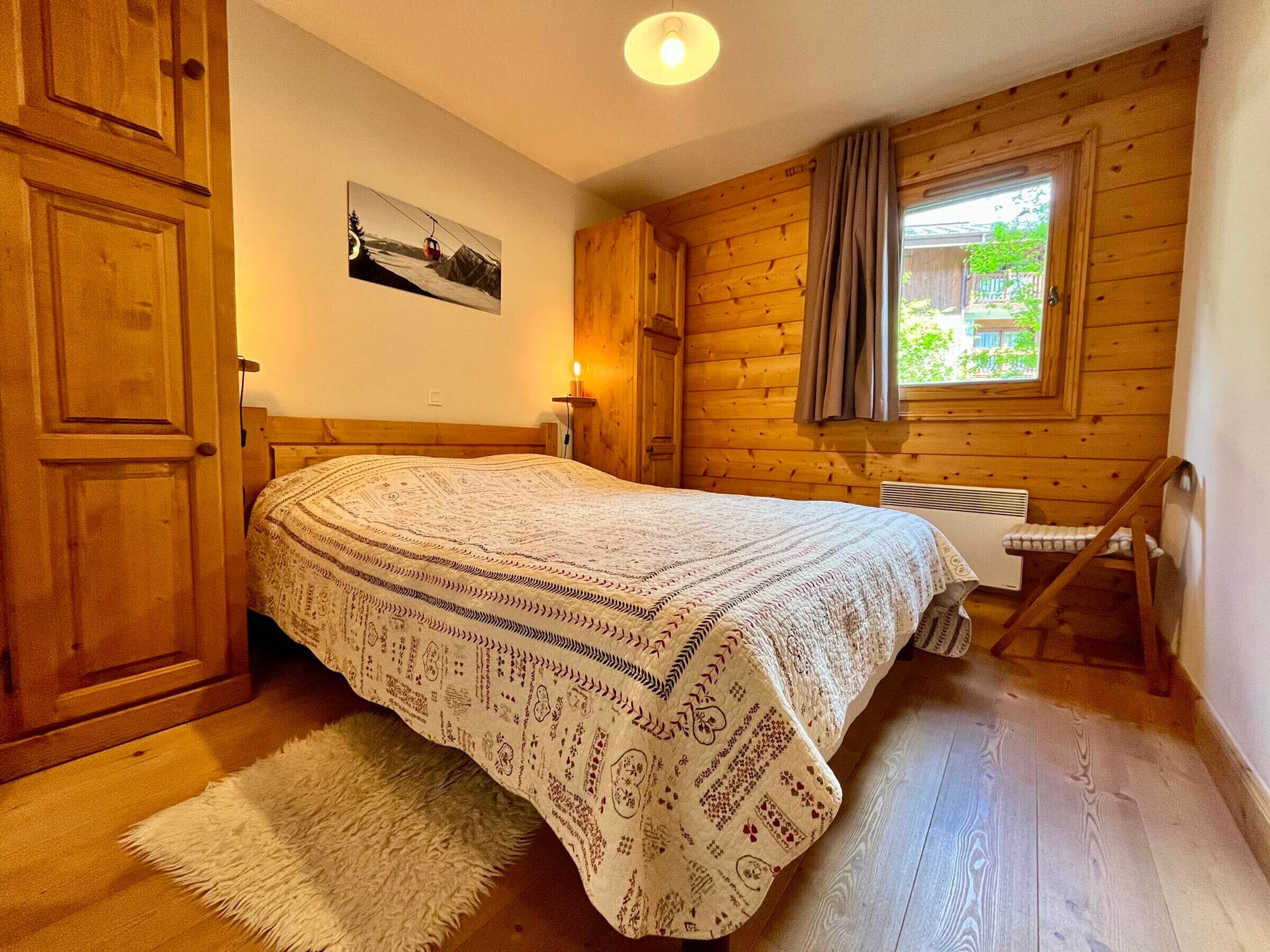 Ett mysigt rum i en stuga med träpanel, ett säng, ett fönster med gardiner och en tavla på väggen.