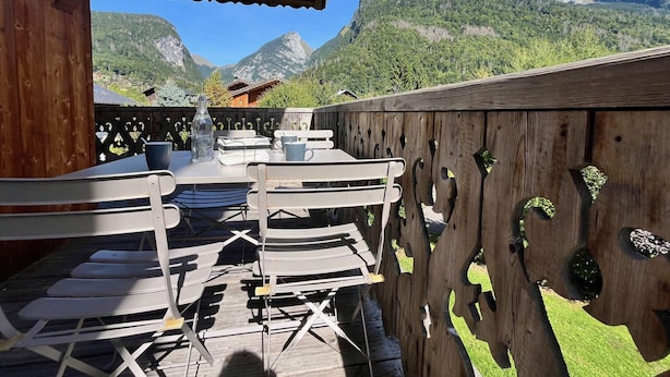 A wooden deck with outdoor seating and a view of mountains. - Comfortable apartment near center with balcony and parking (Samoëns)