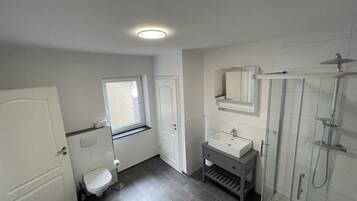 Een douche, handdoeken, zeep, toiletpapier